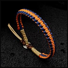 an orange and blue braided bracelet on a black surface