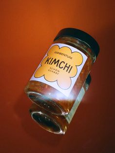 a glass jar filled with food on top of a red table next to an orange wall