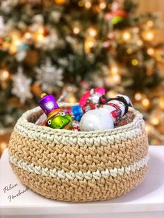 a crocheted basket filled with toys next to a christmas tree