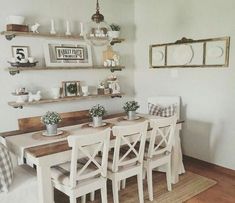 the dining room table is set with white chairs and place settings on shelves above it