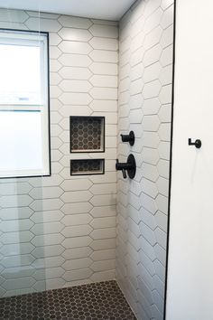 a white tiled bathroom with black accents