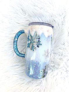 a blue and white coffee mug with snowflakes on it sitting on a furry surface