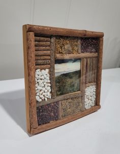 an old wooden frame with pictures and beans in it on a white tablecloth background