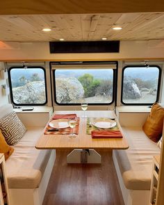 a table with plates and glasses on it in front of two windows that look out onto the ocean