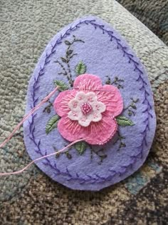 a piece of felt with a flower on it sitting on the ground next to some thread