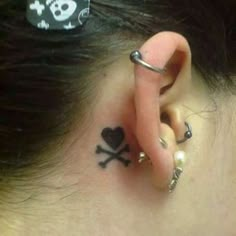 a person with a skull and crossbone tattoo behind their ear is wearing a pair of piercings