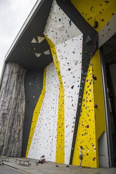 a man climbing up the side of a building with yellow and white paint on it