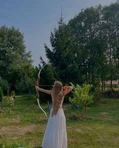 a woman in a white dress holding a bow and arrow