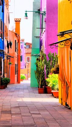 an alley way with colorful buildings and potted plants