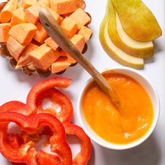 an assortment of fruits and vegetables are arranged on a white plate with a wooden spoon