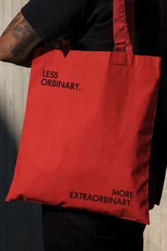 a man carrying a red bag with less ordinary words printed on the front and side