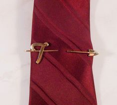 Great Hickok tie clip or tie bar.  The gold tone tie clip has a script "T" at one end and an arrow at the other.  Your tie would slip between the two ends and then the clip on the back clips to your shirt underneath your tie.  Great gift for a gentleman whose name starts with "T".  Made in U.S.A. Vintage 1970's circa Hallmarks - Signed HICKOK U.S.A. on back. Measurements - 3 1/4" long by about 1" tall. Condition - Very good. Comes in a small box, perfect for gift giving. Please review all photos and use the zoom feature.  The item photographed is the exact one you will receive.  Due to lighting effects, monitor's brightness, contrast and other settings, there might be some slight differences in the color tone/shade of the photo and the actual item.  Please consider that vintage and estate Shirt Clips, Vintage Native American Jewelry, A Script, A Gentleman, Tie Pin, Tie Clips, Tie Tack, Tie Bar, Tie Accessories