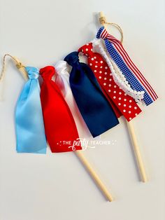 four different colored ties on wooden sticks with white polka dots and red, blue, and white ribbons