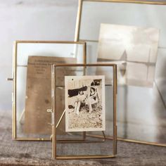 an old photo in a glass frame on top of a wooden table next to other photos