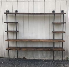 a wooden shelf sitting next to a wall with metal pipes on it's sides