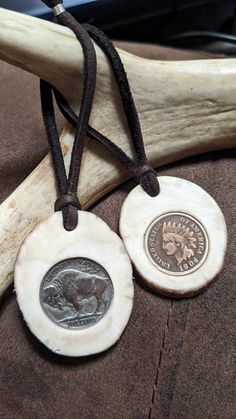 two coins are sitting on a piece of driftwood next to an antler's tooth