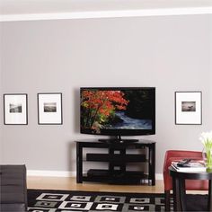 a flat screen tv sitting on top of a wooden stand in a living room next to a red chair