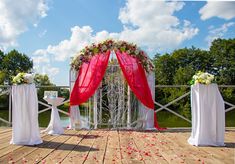 an outdoor wedding setup with red drapes and flowers