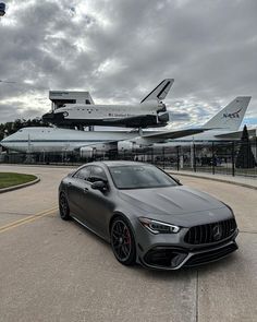 the mercedes amg gts is parked in front of an airplane and space shuttle