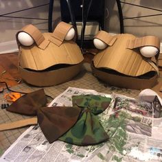 two paper mache heads sitting on top of a table next to scissors and tape