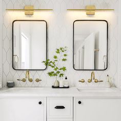 two mirrors on the wall in a bathroom with double sinks and gold faucets