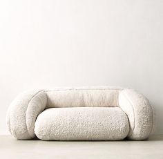 a white couch sitting on top of a floor next to a wall