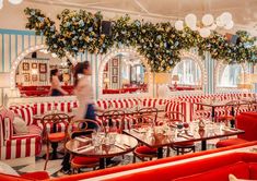 the interior of a restaurant with red and white striped booths, tables, and chairs