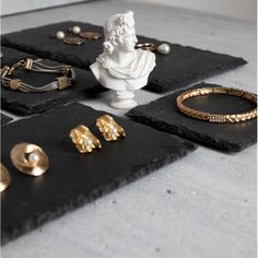 gold jewelry is laid out on the floor in front of a white busturine