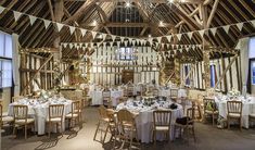 the inside of a barn with tables and chairs set up for a formal dinner or function