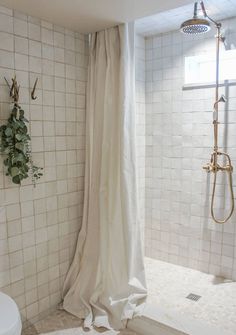 a bathroom with a shower and white tiled walls