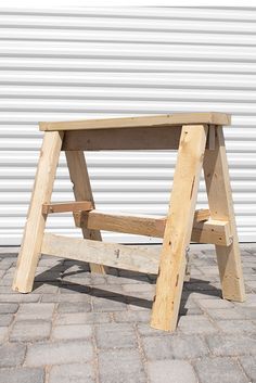 a small wooden table sitting on top of a brick floor next to a garage door