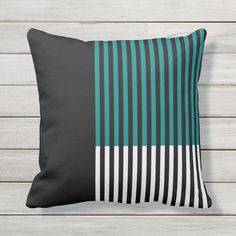 a black and teal striped pillow sitting on top of a white wooden floor next to a wall