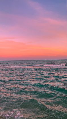 a person riding a surfboard on top of a wave in the ocean at sunset