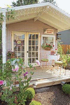 a small house with lots of plants and flowers on the front porch, next to a deck