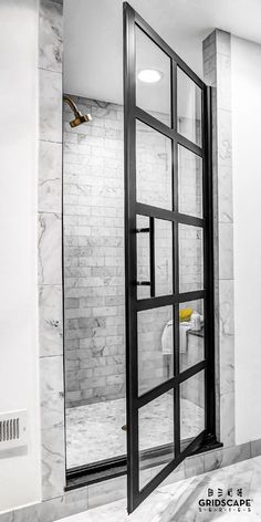 an open door leading into a bathroom with marble walls and flooring in black and white