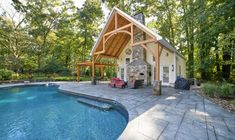 a house with a pool and covered patio next to the swimming pool is surrounded by trees