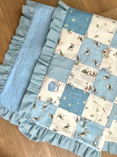 a blue and white patchwork baby quilt on the floor with it's edges folded