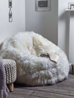 a white bean bag chair sitting on top of a wooden floor next to a wall