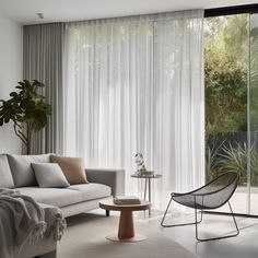 a living room filled with furniture and a large window covered in white drapes