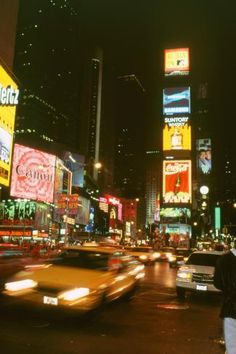 a busy city street filled with lots of neon signs and cars driving down the road