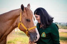 a woman standing next to a brown horse