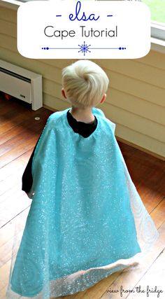 a little boy wearing a cape in front of a window