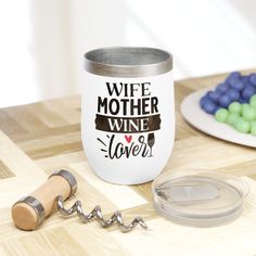 a wine glass sitting on top of a wooden table next to a corkscrew