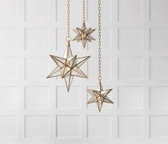 three gold stars hanging from chains against a white wall