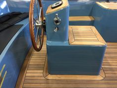 the inside of a boat with wooden flooring and steering wheel on it's side