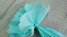 a close up of a tissue paper flower on a wooden table with wood grained background