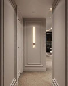 an empty hallway with white walls and wood flooring is lit by modern lighting fixtures