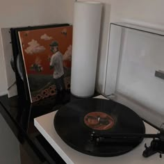 a record player sitting on top of a white table next to a black and orange poster