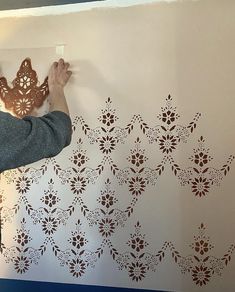 a man is painting a wall with brown stencils