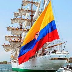 a large white ship with a rainbow flag on it's mast in the water